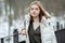 Cold season young beautiful woman in white coat with disheveled hair posing on park bridge lifestyle concept portrait