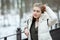 Cold season young beautiful woman in white coat touching hair posing on park bridge lifestyle concept portrait