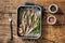 Cold Smoked sprat fishes in a kitchen tray with spices. Wooden background. Top view