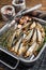 Cold Smoked sprat fishes in a kitchen tray with spices. Wooden background. Top view