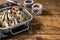 Cold Smoked sprat fishes in a kitchen tray with spices. Wooden background. Top view. Copy space