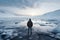 Cold spring day, man gazes at icy lake from beach