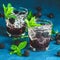 Cold summer berry drink with blackberries. Refreshing summer drink with syrup, blackberry and ice on dark blue concrete background