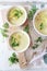 Cold summer zucchini cream soup, three portions on light background, vegetable food