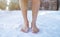 Cold training and acclimation concept. Senior guy standing barefoot on snow at winter forest, cropped view