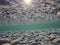 Cold underwater river bed with perfect reflection on surface tension