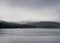 The cold waters of Pontsticall Reservoir with the forests and moorlands of the Brecon Beacons behind. On a grey moody misty autumn