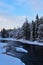 Cold winter afternoon in Koiteli rapids. Frozen river, dense spruce forest.