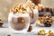 Cold winter chocolate dessert with whipped cream, popcorn and caramel topping in glasses on beige background, place for text