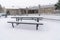 Cold winter day at a park with picnic tables and benches covered with snow