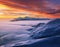 Cold winter morning. Amazing sky with orange cloud. Fantastic sunrise illuminates the mountain, thick fog and horizon.