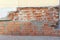 The collapsed corner of the old brick house is repaired with a fresh masonry of red brick.