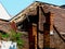 Collapsed old clay tile sloped house roof with chimney. Overgrown with small tree and weed