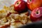 Collapsed soft baked apples in a white ceramic square shape on a special package. A white tablecloth is laid carelessly on the tab