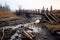 collapsed wooden bridge with a dried-up riverbed