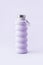 Collapsible reusable lilac water bottle on purple background. Sustainability eco-friendly lifestyle