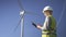 Collar worker standing near wind mill and using program on device