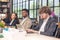 Colleagues in a boardroom discussion, seated at a table together, swapping ideas and strategizing project strategy. In the office