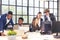 Colleagues in a boardroom discussion, seated at a table together, swapping ideas and strategizing project strategy. In the office