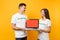 Colleagues couple in white t-shirt inscription volunteer hold laptop pc computer, blank empty screen isolated on yellow