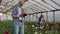 Colleagues florists work together with tablet computers in a rose-growing greenhouse. Small business doing flower check