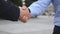 Colleagues meet and shake hands in the city background. Two businessmen greeting each other in urban environment