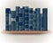 Collection of blue books on a bookshelf on a background of light wallpaper. Ornate book spines with space for text