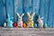 A collection of colorful eggs and funny handmade textile Easter bunnies on a blue wooden background.