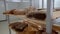 Collection of fresh baked breads is on the wooden shelves of  cart in a bakery