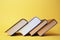 Collection of hardcover books on yellow background, space for text