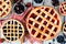 Collection of homemade fruit pies over a rustic white wood table background