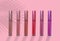 collection of liquid glossy lipstick tube on background, red, raspberry, pink, coral, peach color close-up, concept of decorative