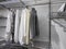 Collection of monotone colored tops and bottoms hanging inside an organized walk in closet with metal wire rack shelving