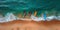 A collection of vibrant surfboards is lined up neatly on a sandy beach, adding a pop of color against the backdrop of