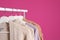 Collection of warm sweaters hanging on rack against color background.