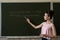 college female student writing on blackboard completing mathematical equations