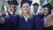 College graduates taking selfie on graduation day saying cheese, friendship