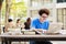 College student boy reading book for exam and listening to music via headphones with laptop. Youth student and tutoring education