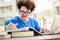 College student boy reading book for exam and listening to music via headphones with laptop. Youth student and tutoring education