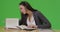 A college student does her homework at her desk in her room on green screen