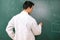 College student in laboratory class, with white coat , writing on chalkboard.