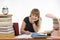 College student smiling engaged at table cluttered with books in the library