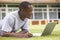 College student using laptop on campus lawn