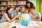 College students pointing at globe in library