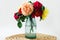 Coloful roses in vase on a wicker napkin on white background