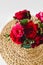 Coloful roses in vase on a wicker napkin on white background