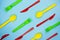 Colofulr plastic cutlery on light blue background. Pattern of green forks, yellow spoons and red knives