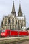 COLOGNE, GERMANY - April 7 2018: Rear view of Cologne railway station with red train. Cathedral tower on background