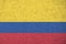 Colombia flag depicted in bright paint colors on old relief plastering wall. Textured banner on rough background