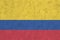 Colombia flag depicted in bright paint colors on old relief plastering wall. Textured banner on rough background